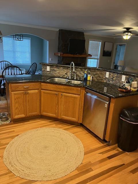 kitchen featuring dishwasher, decorative backsplash, dark stone counters, and sink