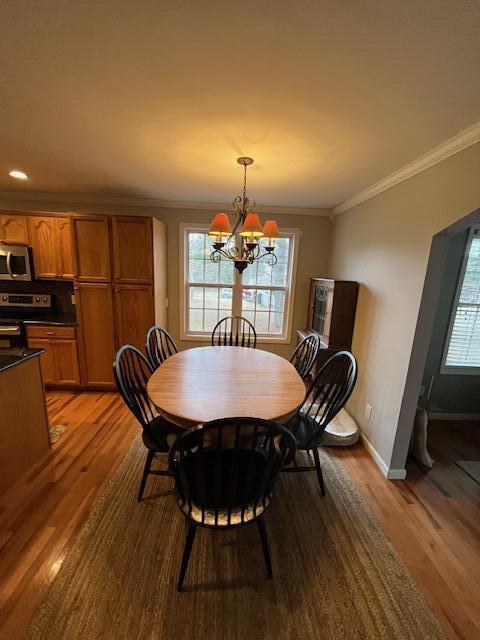 dining area with light hardwood / wood-style floors, crown molding, and a chandelier