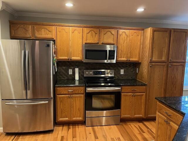 kitchen with dark stone counters, ornamental molding, appliances with stainless steel finishes, and tasteful backsplash