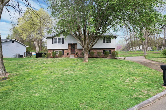 bi-level home with a front yard, brick siding, and aphalt driveway