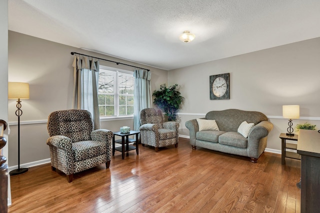 living room with hardwood / wood-style floors, a textured ceiling, and baseboards