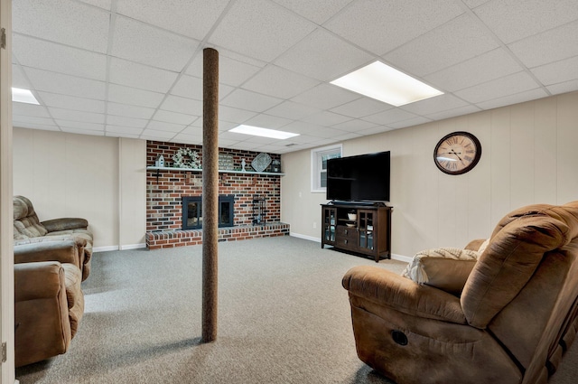 carpeted living area featuring baseboards, a fireplace, and a drop ceiling