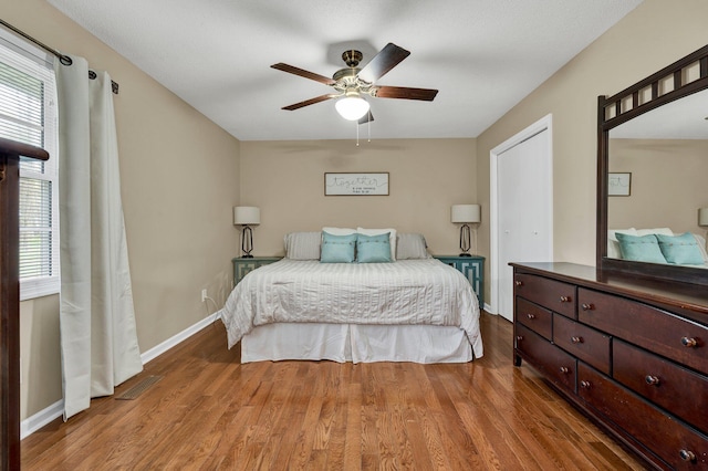 bedroom with multiple windows, wood finished floors, and baseboards