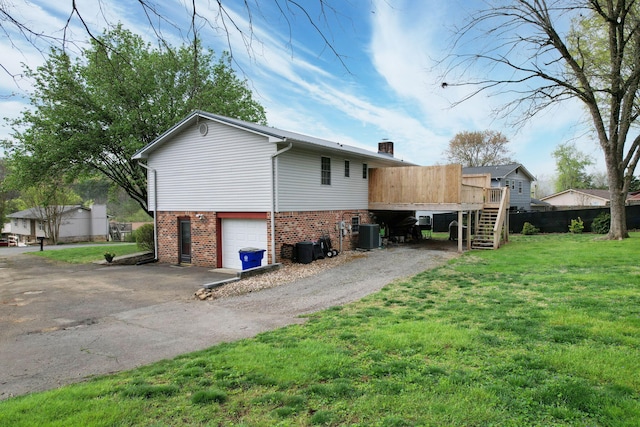 view of home's exterior with driveway, a chimney, an attached garage, brick siding, and a yard