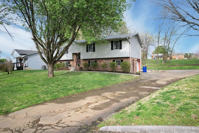 bi-level home with aphalt driveway, a garage, brick siding, and a front yard