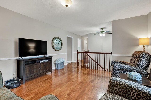 living room featuring baseboards, light wood-style flooring, and ceiling fan