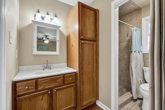 full bathroom with vanity, toilet, a tile shower, and a ceiling fan