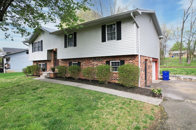 bi-level home with brick siding, driveway, an attached garage, and a front lawn