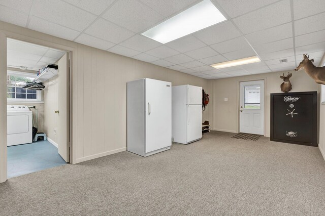 below grade area featuring light colored carpet, a paneled ceiling, washer / dryer, and freestanding refrigerator