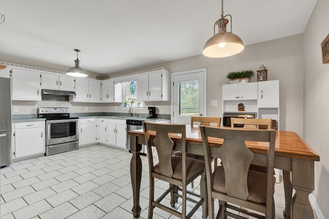 kitchen featuring a sink, decorative light fixtures, appliances with stainless steel finishes, and under cabinet range hood