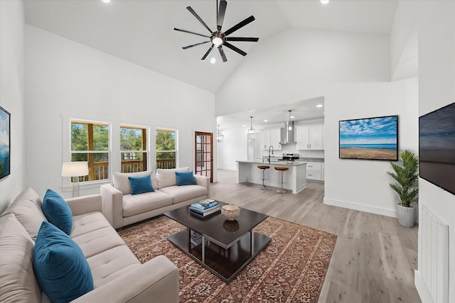 living area featuring recessed lighting, light wood-style flooring, a ceiling fan, high vaulted ceiling, and baseboards