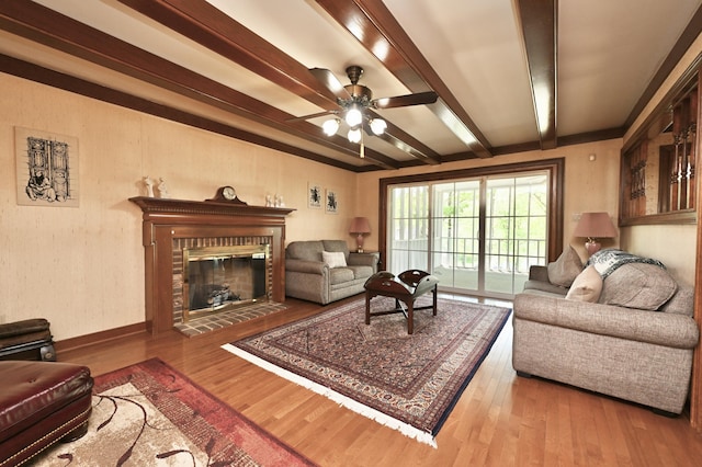 living room with ceiling fan, wood finished floors, beamed ceiling, and a fireplace