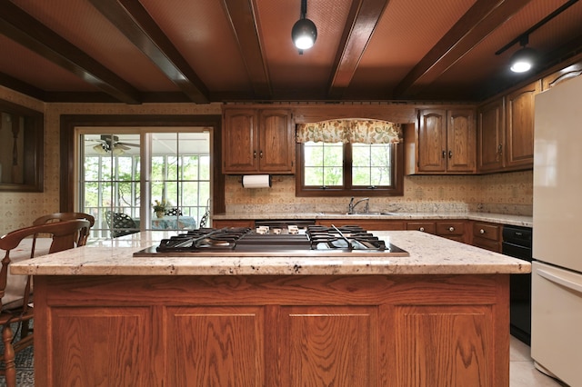 kitchen with a sink, freestanding refrigerator, a center island, decorative backsplash, and stainless steel gas cooktop