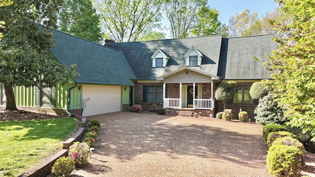 new england style home featuring driveway, covered porch, brick siding, an attached garage, and a shingled roof
