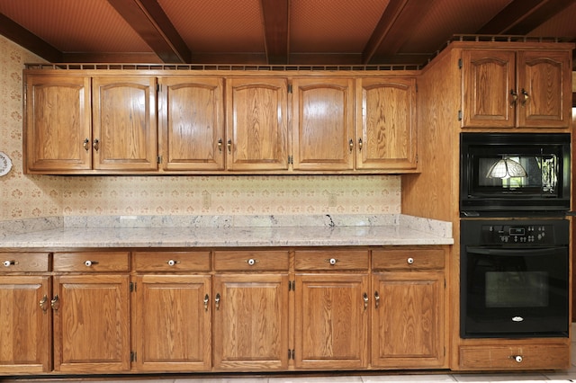 kitchen featuring brown cabinetry, black appliances, light stone countertops, and beamed ceiling