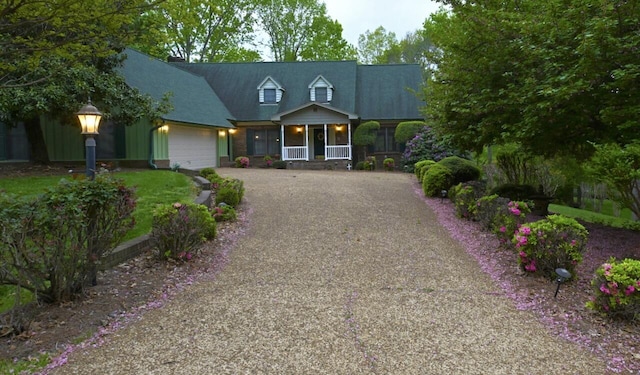 cape cod-style house with an attached garage, driveway, and covered porch