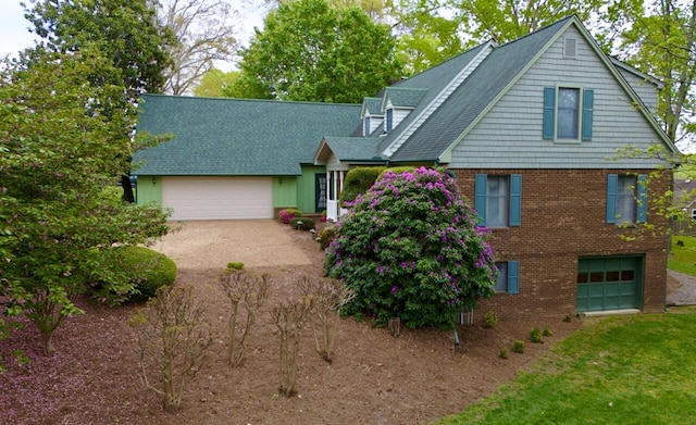 view of front of property featuring brick siding, driveway, roof with shingles, and a garage