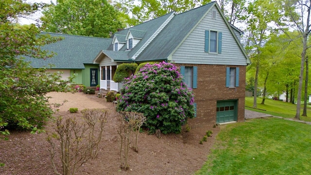 back of property with a garage, a yard, brick siding, and a shingled roof