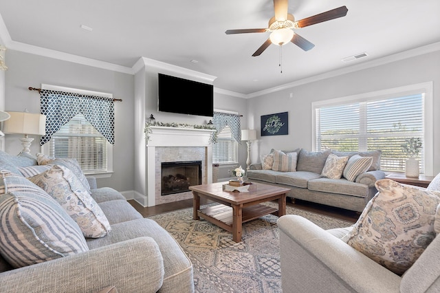 living room with crown molding, a healthy amount of sunlight, a fireplace, and light wood-type flooring