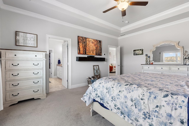 carpeted bedroom with crown molding, connected bathroom, a tray ceiling, and ceiling fan