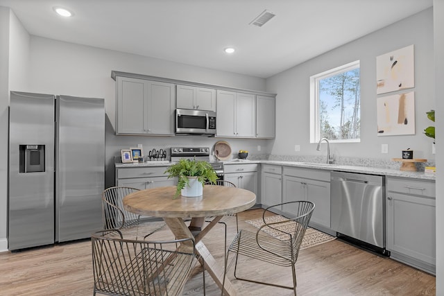 kitchen with stainless steel appliances, sink, light hardwood / wood-style flooring, and gray cabinetry