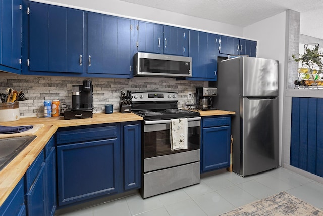 kitchen with blue cabinets, stainless steel appliances, and butcher block counters