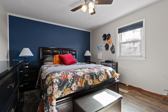 bedroom with ceiling fan, baseboards, and wood finished floors