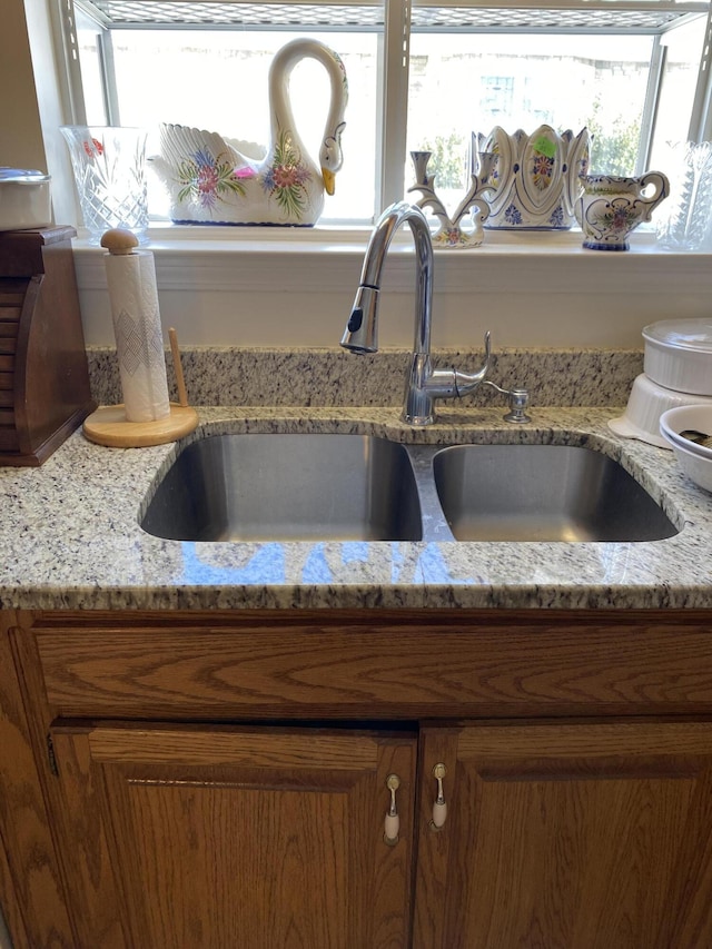 interior details with a sink, light stone countertops, and brown cabinets