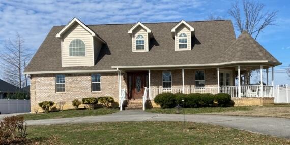 view of front facade with driveway, a porch, and a front yard