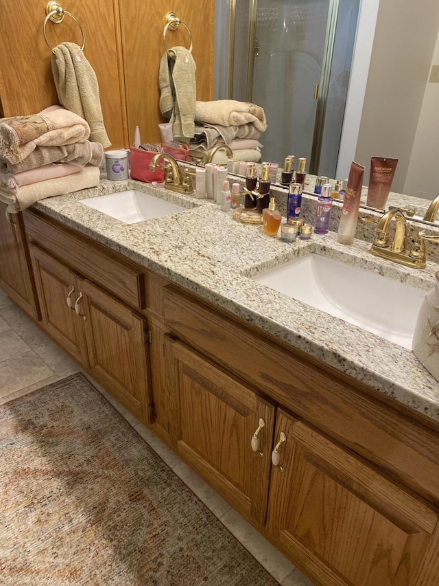 bathroom featuring double vanity, tile patterned floors, a sink, and a shower stall