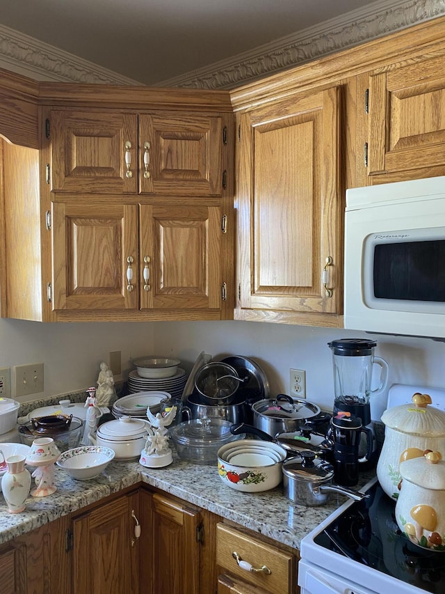 kitchen with light stone counters, white appliances, and brown cabinets