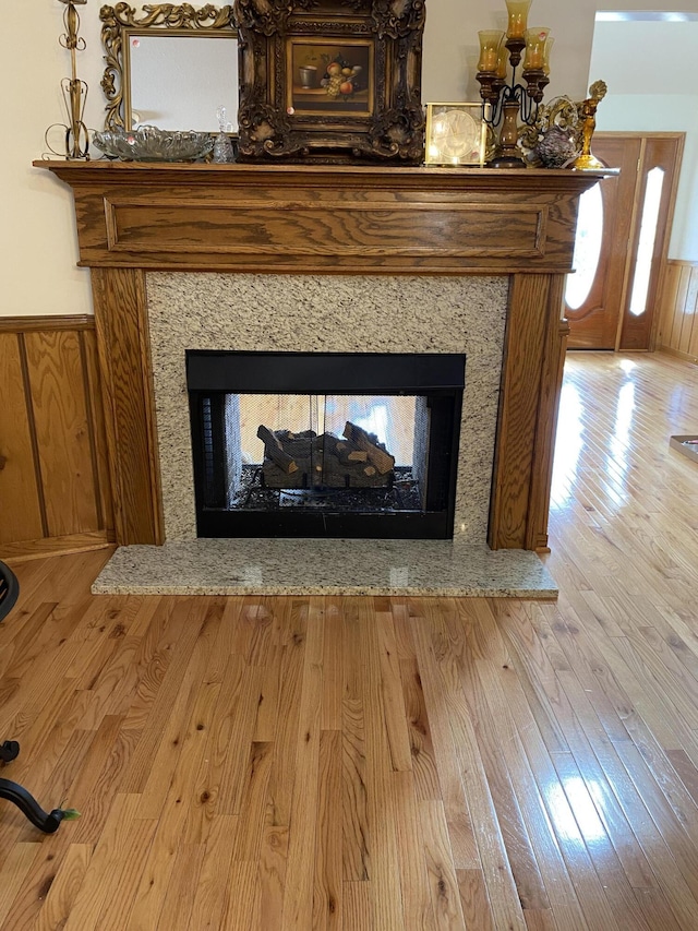 interior details with a multi sided fireplace, wood finished floors, and wainscoting