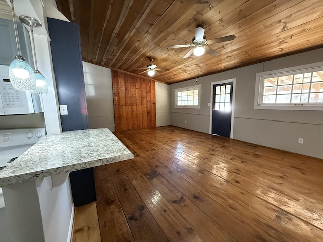 interior space with dark hardwood / wood-style flooring, ceiling fan, wood ceiling, and wood walls