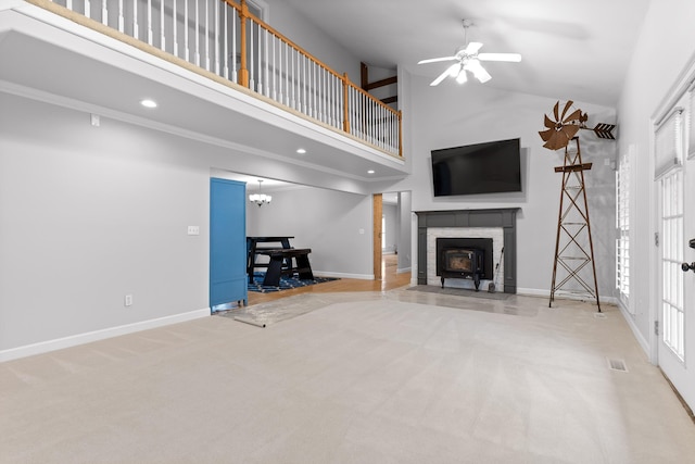 unfurnished living room featuring ceiling fan with notable chandelier, high vaulted ceiling, and light carpet