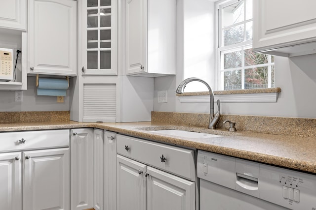 kitchen with white cabinetry, sink, and white dishwasher