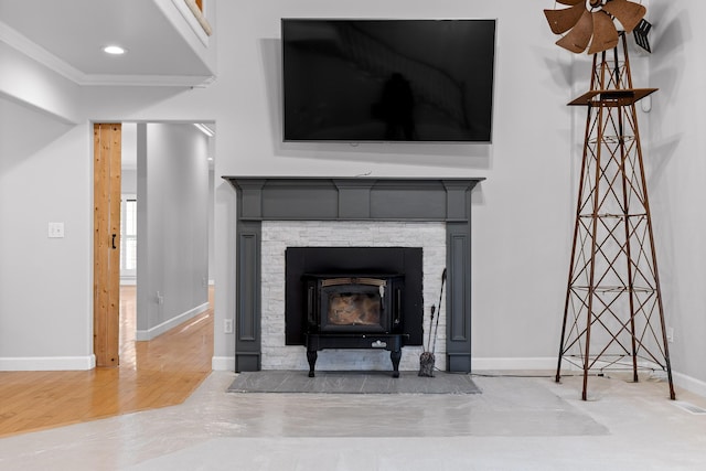 interior details with hardwood / wood-style flooring, ornamental molding, and a wood stove