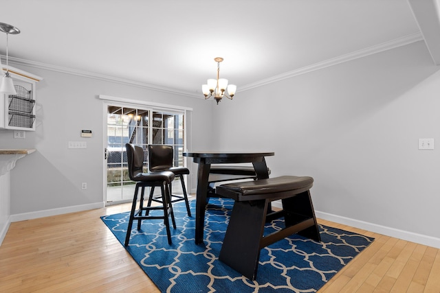 dining area with crown molding, a notable chandelier, and hardwood / wood-style flooring