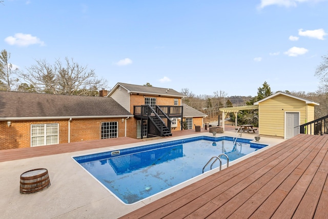 view of swimming pool featuring a storage shed, a wooden deck, and a pergola