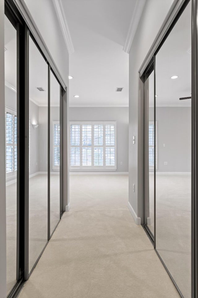 corridor with light colored carpet, ornamental molding, and plenty of natural light