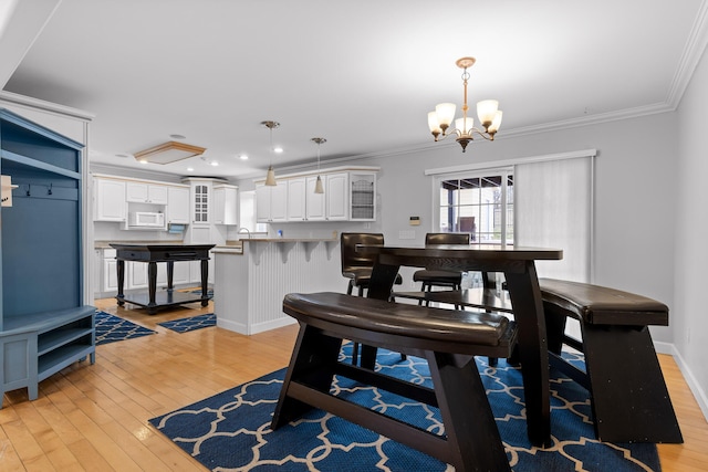 dining area with ornamental molding, a chandelier, and light hardwood / wood-style flooring