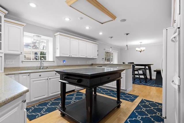 kitchen featuring sink, crown molding, decorative light fixtures, light wood-type flooring, and white cabinets