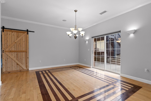 empty room featuring crown molding, a barn door, a chandelier, and light wood-type flooring