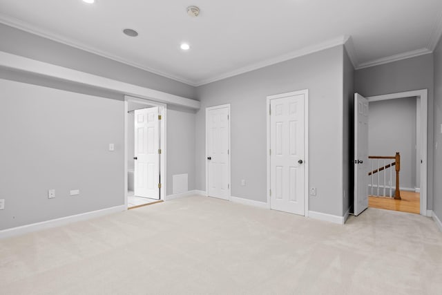 unfurnished bedroom with light carpet, crown molding, and two closets