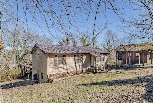 view of front of house with central AC, metal roof, and a front lawn