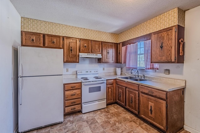 kitchen with wallpapered walls, white appliances, a sink, and under cabinet range hood