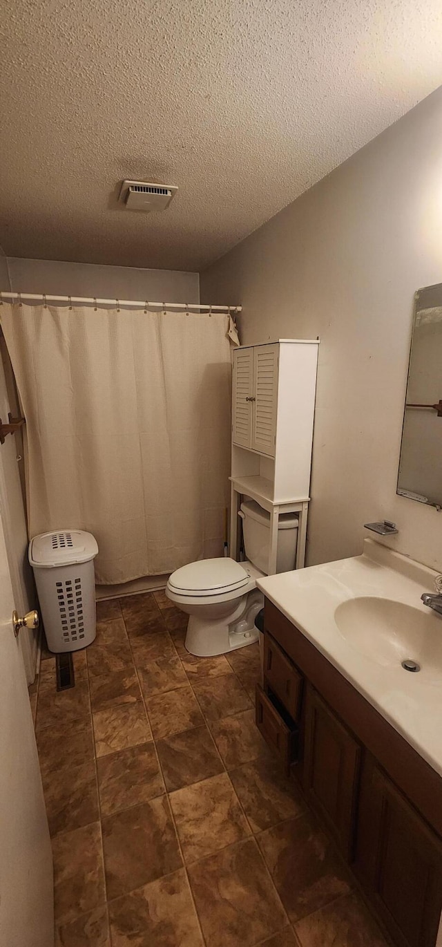 bathroom with toilet, visible vents, a textured ceiling, and vanity