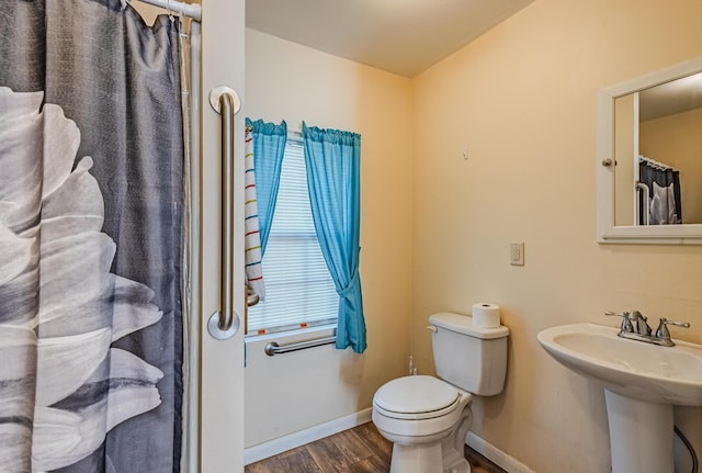 full bathroom with curtained shower, toilet, a sink, wood finished floors, and baseboards