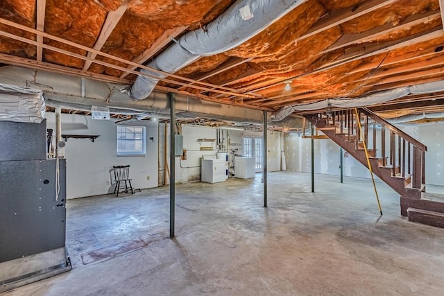 basement featuring stairs, electric panel, and heating unit