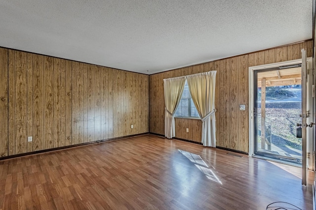 empty room featuring a textured ceiling, wood finished floors, and baseboards