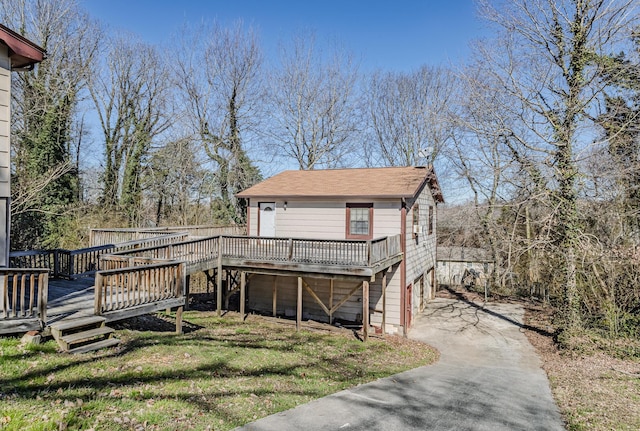 view of front facade with a deck, driveway, and a front yard